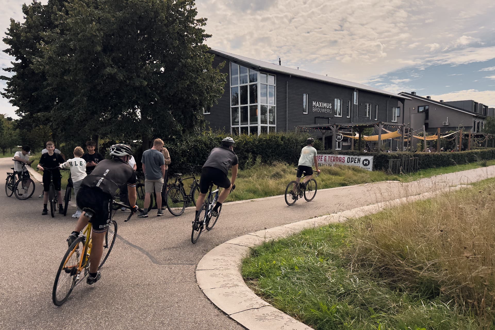 Fietsers rijden langs Brouwerij Maximus